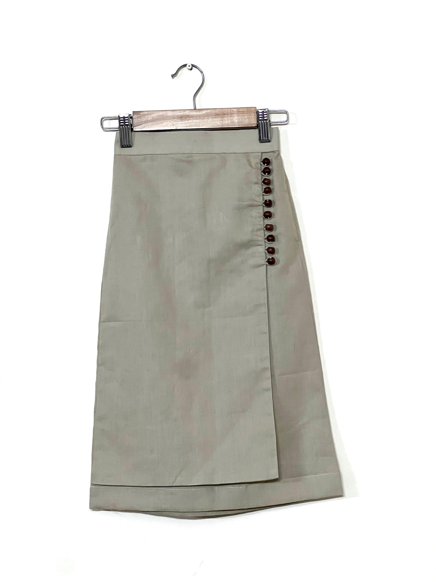Beige linen co-ord set for young girls featuring a sleeveless top with side ties and a wrap skirt with wooden button details—perfect for stylish comfort.