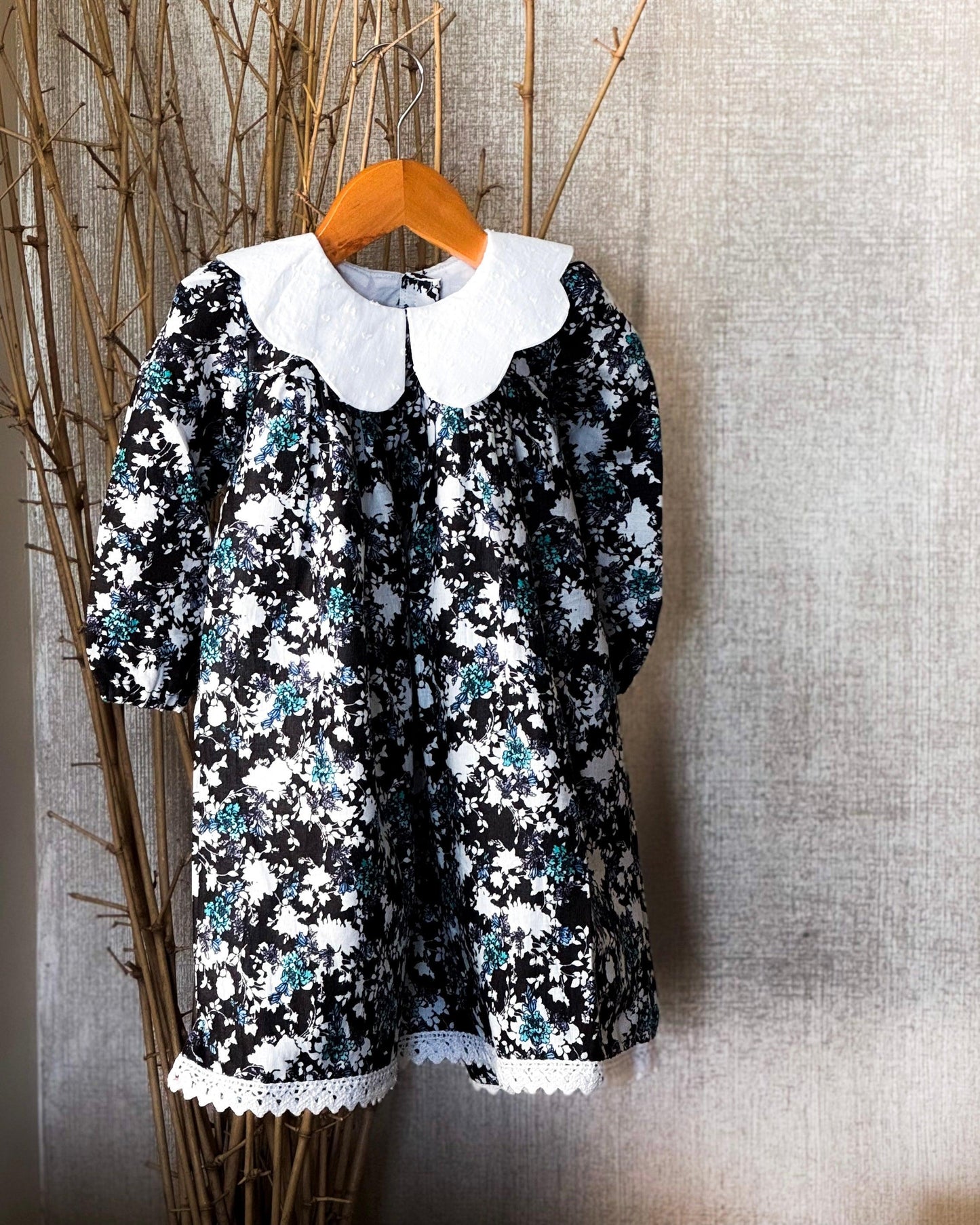 Vintage floral black cotton dress for girls with white Peter Pan collar and lace-trimmed hem, perfect for special occasions and everyday wear.