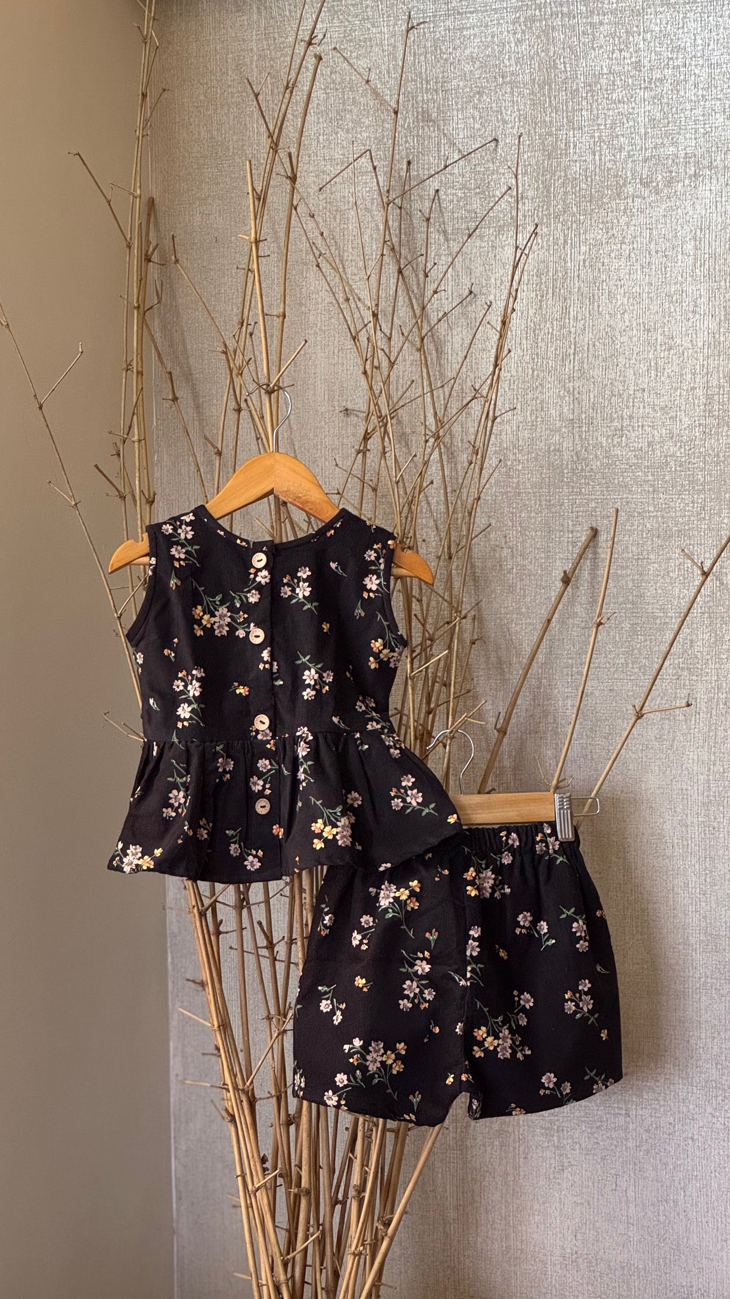 Girls’ black floral soft corduroy co-ord set with a sleeveless peplum top and high-waisted shorts—stylish, breathable, and perfect for any occasion.