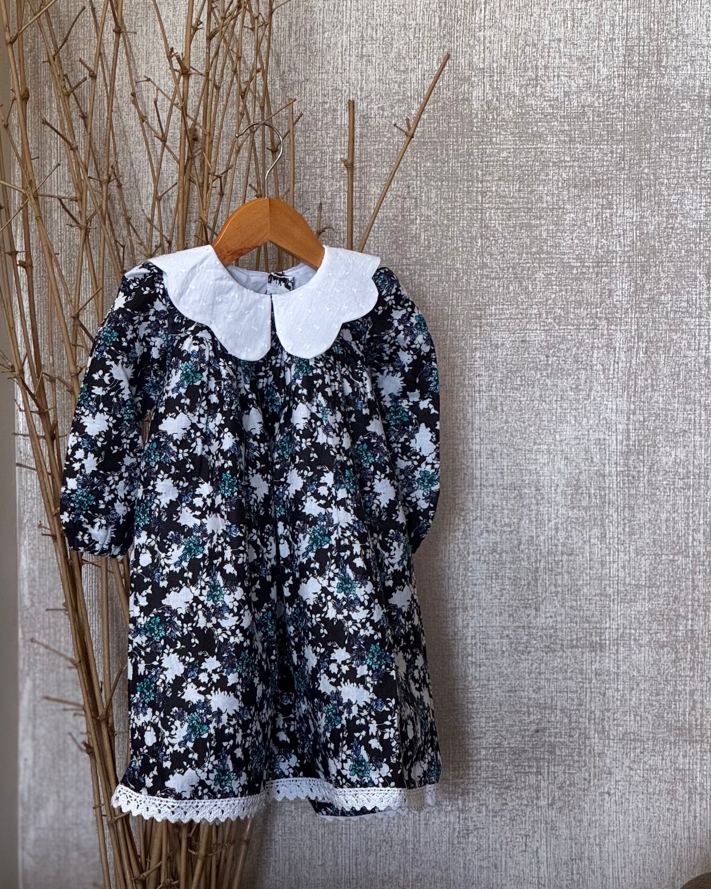 Vintage floral black cotton dress for girls with white Peter Pan collar and lace-trimmed hem, perfect for special occasions and everyday wear.