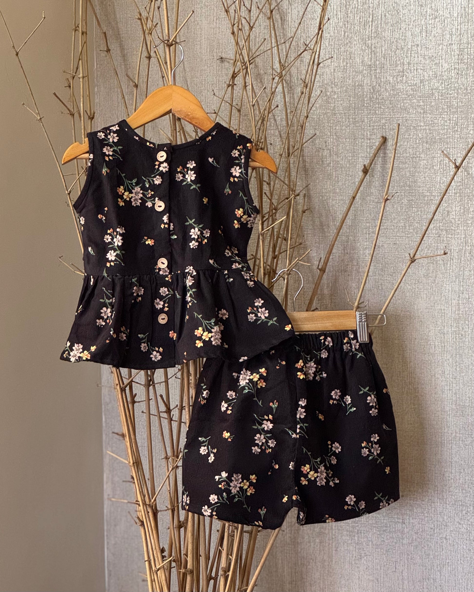 Girls’ black floral soft corduroy co-ord set with a sleeveless peplum top and high-waisted shorts—stylish, breathable, and perfect for any occasion.
